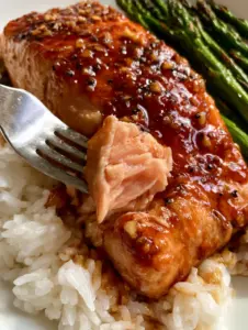 Overhead view of glistening brown sugar salmon fillets in a skillet with bubbling dark soy glaze.