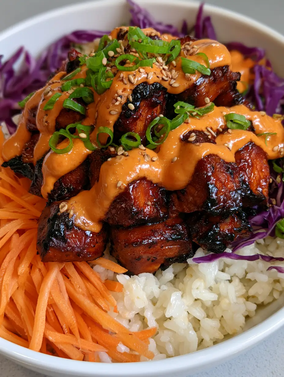Close-up of charred gochujang glazed chicken cubes in a bowl with rice. (korean bbq chicken bowls)