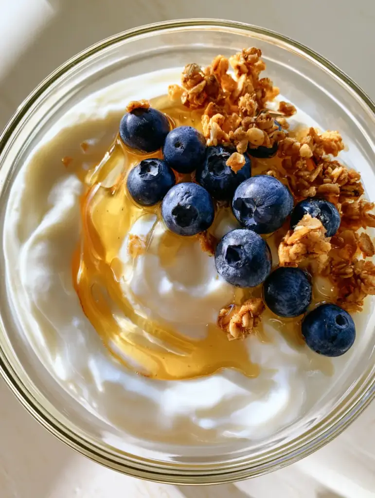 Pressure Cooker Yogurt: The Ultimate Guide to Creamy Homemade Perfection 1 Close-up of golden honey swirling into pristine white pressure cooker yogurt with granola.