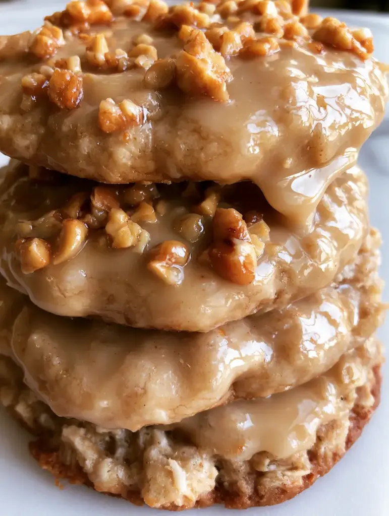 Top-down close-up of three peanut glazed oatmeal cookies showing the shiny caramel-colored glaze and glistening peanut pieces.