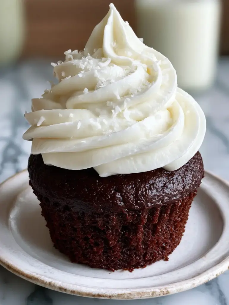 A vertical photo showing the creamy texture and defined ridges of whipped coconut frosting on a white ceramic plate.