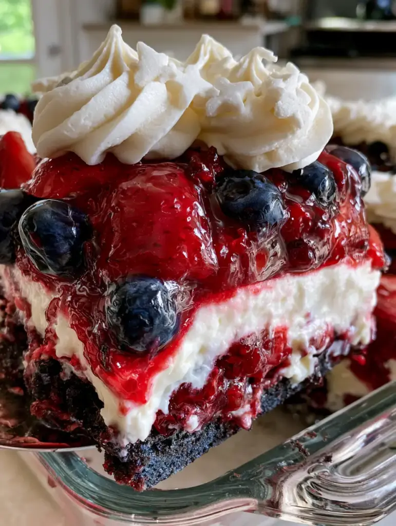A slice of berry dessert lasagna on a plate showing perfect whipped cream peaks and star sprinkles.